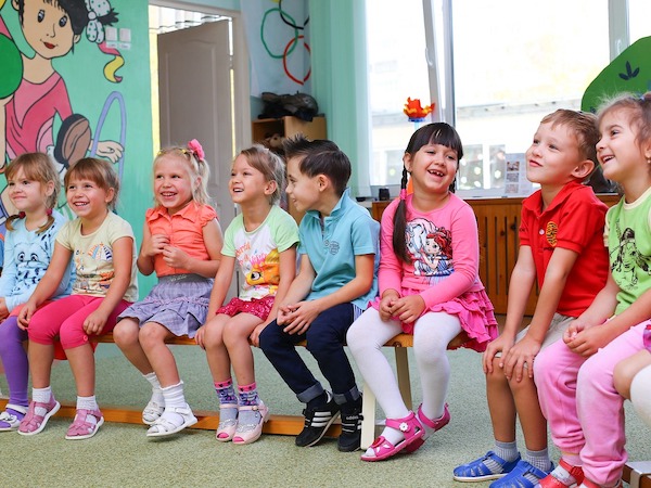 Das Bild zeigt ein kleines Mädchen mit bunt bemalten Händen und Gesicht.